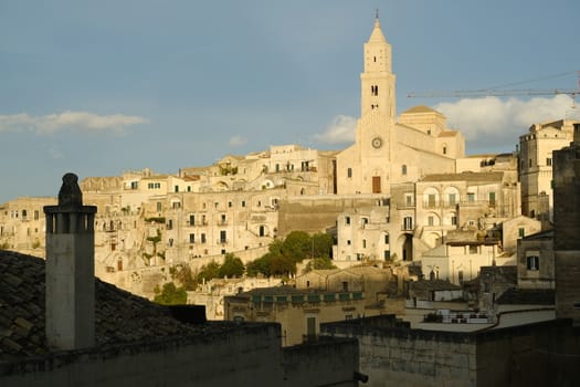 Cathedral Church of the Madonna della Bruna and of Sant'Eustachio in Matera. House with funnel in the foreground. Morning light.