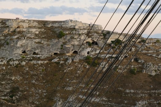 Bundle of telephone cables with the background of ancient caves used as houses.