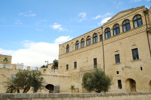 Facade of the Convent of Sant'Agostino in Matera. Courtyard with olive trees with leaves moving in the wind.