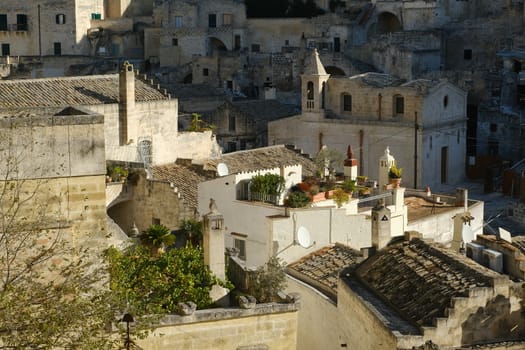 Roofs of houses in the Sassi of Matera transformed into hotels. In the background an ancient church.