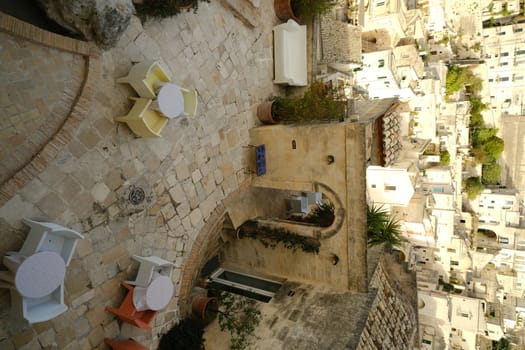 Matera, Basilicata, Italy. About 11/2019. Roofs of houses in the Sassi of Matera transformed into hotels. Panoramic terrace with sofa and chair in white plastic.