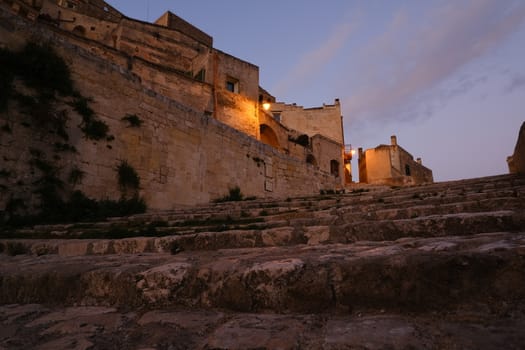 Deserted street with night light in the city of Matera in Italy. Beige tufa stone houses.