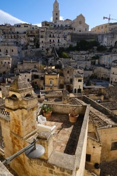 Roofs of houses in the Sassi of Matera transformed into hotels. Panoramic terrace with sofa and chair in white plastic.