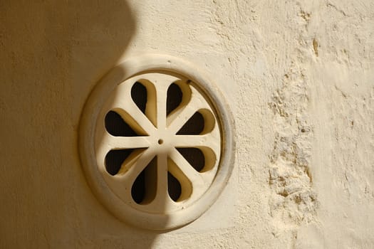 Matera, Italy. About 11/2019. Ventilation grid on the front of a house. Made of stone with a decorative shape.  Matera, Italy.