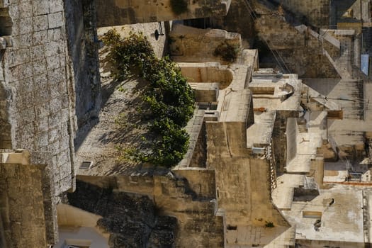 Roofs of houses in the Sassi of Matera transformed into hotels. Wall in beige tuff with grapevine plant.