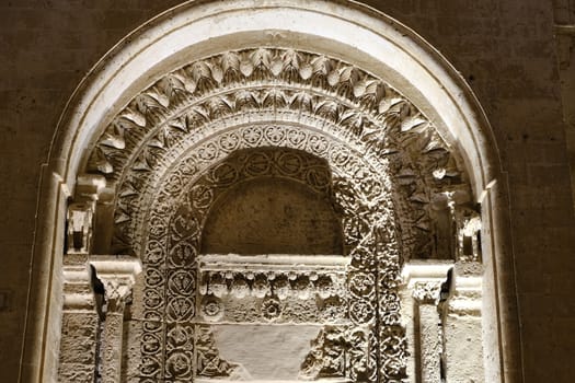 Night photo of the facade of the church of San Giovanni in Matera. Photographed with artificial lights. Detail of the portal in Arabic style.