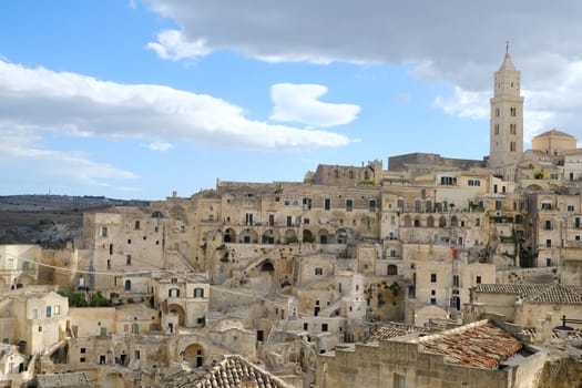 View of the city of Matera in Italy. Church with bell tower and houses built in beige tuff stone.