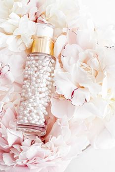 Luxurious cosmetic bottle as antiaging skincare product on background of flowers, blank label packaging for body care branding design