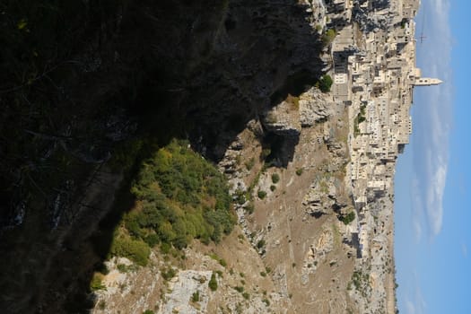 Panorama of houses and of the Sassi of Matera with roofs and streets. Blue sky with church and bell tower with blue sky background with clouds.