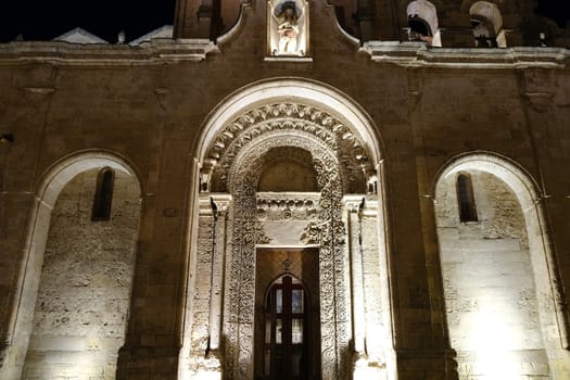 Night photo of the facade of the church of San Giovanni in Matera. Photographed with artificial lights. Detail of the portal in Arabic style.