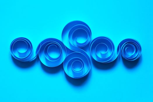 Abstract composition made from paper spirals on blue background