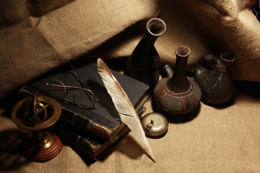 Vintage still life with old books and quill pen on canvas background