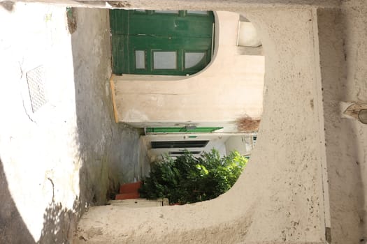Typical Mediterranean courtyard with white walls, with vaults, plants and a green door.