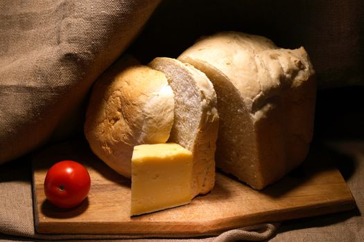 Freshness loaf of white bread near cheese on canvas background