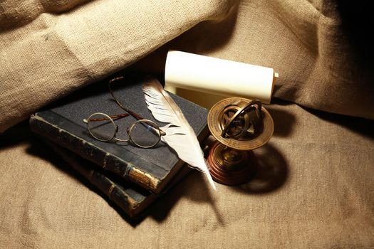 Vintage still life with old books and quill pen on canvas background