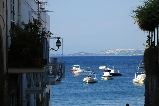 Ischia, Naples, Italy, About the July 2019. Typical houses of the Mediterranean village with the background of the blue sea with boats.