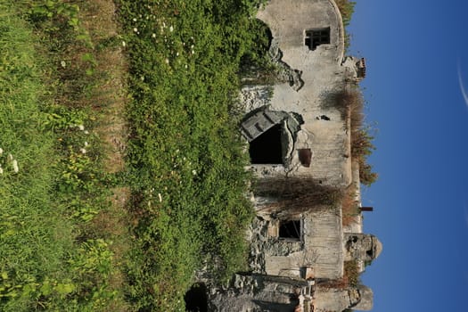 Ancient Mediterranean house in a state of degradation on the island of Ischia in the town of Forio. Green vegetation and blue sky.