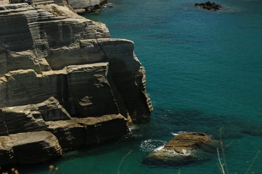 Volcanic rocks and rocks in the Mediterranean sea of Ischia. Close to Naples. The waves of the blue sea break on the cliff.