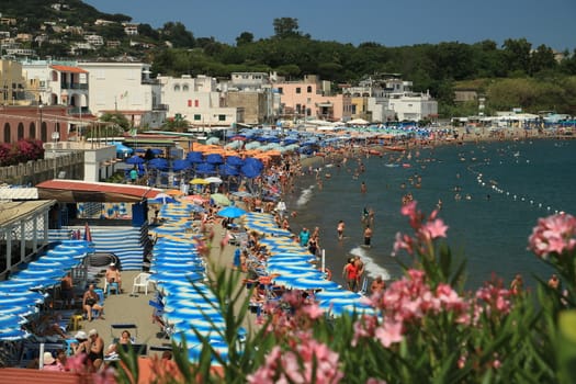 Ischia, Naples, Italy, About the July 2019. Beach with umbrellas, sunbeds and deck chairs. Bathing establishments and houses in the town of Ischia.