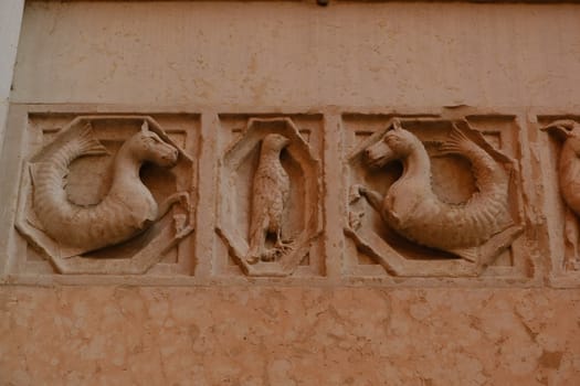 Embossments in relief on the facade of the baptistery of Parma. Sculptures on red marble from Verona