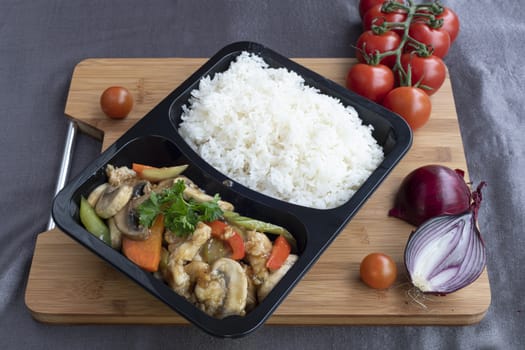 Stir fried chicken with white rice and vegetable served in a recipent for take away