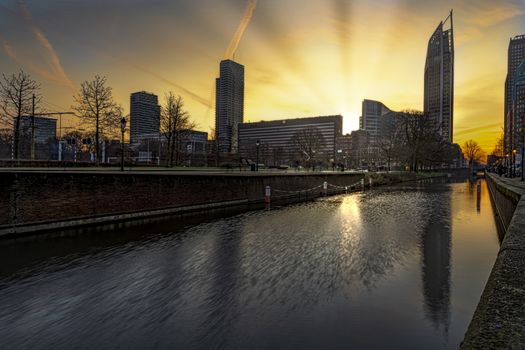 View of The Hague sunrise, early morning skyline reflected on the calm canal's water, Netherlands