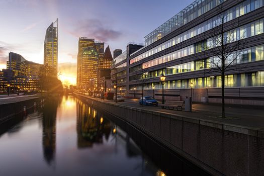 View of The Hague sunrise, early morning skyline reflected on the calm canal's water, Netherlands