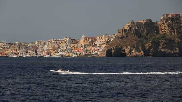 The island of Procida seen from the sea. The village of Corricella with colorful houses and the ancient castle on the mountain.