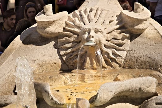 Barcaccia Fountain in Piazza di Spagna in Rome. Rome Italy. 05/02/2019.  Detail of a sun-shaped mouth with a human face from which water flows. Pietro Bernini project.