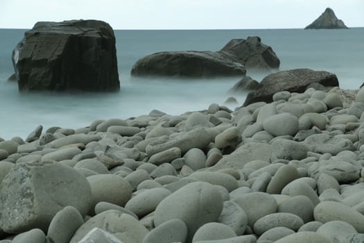 Beach with large stones near the Cinque Terre. Velvety sea with long exposure. Scoglio del Ferale, La Spezia.