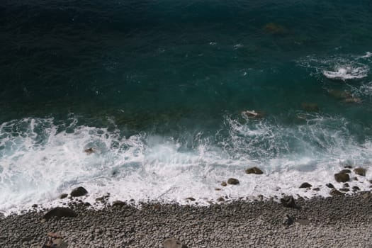 Waves of the sea break on the beach and on the rocks near the Cinque Terre. Uncontaminated wild and natural environment in the Ligurian sea.