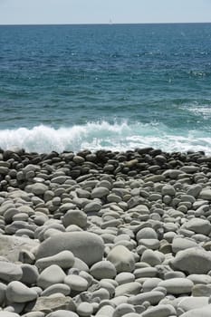 Beach with large stones near the Cinque Terre. Velvety sea with long exposure. Scoglio del Ferale, La Spezia.