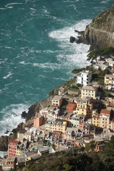 Panorama of the village of Riomaggiore in the Cinque Terre. Rough sea with waves on the cliff.