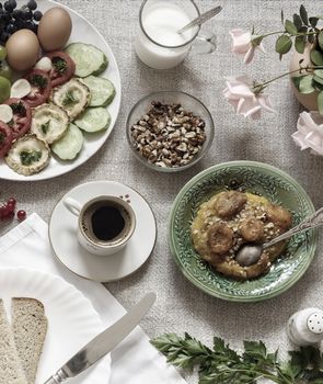 Healthy Breakfast: pumpkin puree with dried apricots, muesli, kefir, vegetables, eggs, coffee. Presented on a homespun rustic tablecloth, top view.