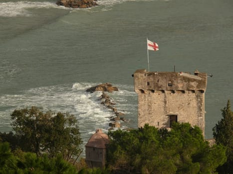 Lerici, Liguria, Italy. About 2/2010. Tower of the castle of San Terenzo in Lerici with the flag of Genoa in the wind. In the background the sea.