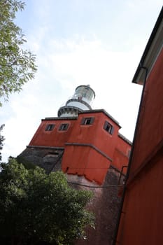 La Spezia, Italy. About 9/2019. Lighthouse of the Isola del Tino, in the Gulf of La Spezia,  Near Cinque Terre. Red painted building and white tower with glass.
