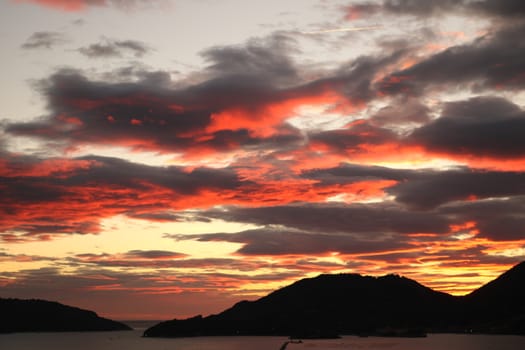 Sky with red-illuminated clouds by the sunset light. Gulf of La Spezia in Liguria.