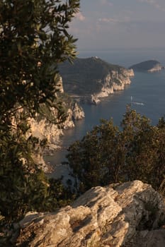 Mountains overlooking the sea near the Cinque Terre. In the background the church of Portovenere and the islands of Palmaria and Tino. Photo at sunset.