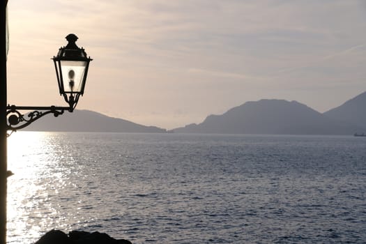 Sunset light on the sea of the Gulf of La Spezia. Street lamp in the marine village of Tellaro, near the Cinque Terre.