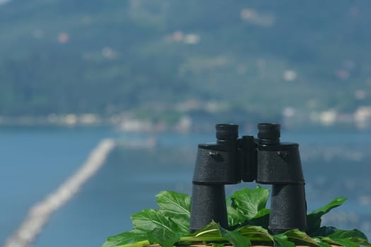 Binoculars resting on a table. Ligurian Mediterranean sea in the Gulf of La Spezia.