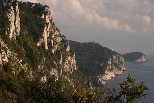 Mountains overlooking the sea near the Cinque Terre. In the background the church of Portovenere and the islands of Palmaria and Tino. Photo at sunset.