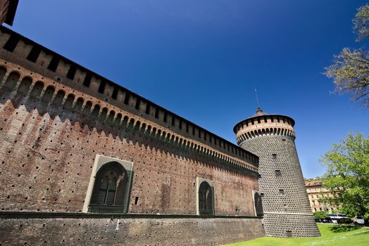 Milan, Lombardy, Italy, 04/27/2019. Sforza Castle. Cylindrical tower and walls. The Castle with the walls and the background of the blue sky of a spring day.