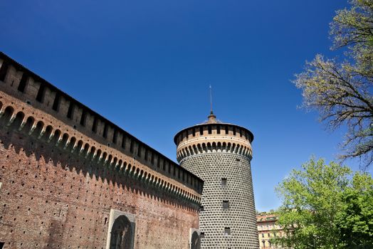 Milan, Lombardy, Italy, 04/27/2019. Sforza Castle. Cylindrical tower and walls. The Castle with the walls and the background of the blue sky of a spring day.