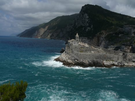 Church of San PIetro in Portovenere, built on a rock overlooking the sea. Sky with clouds and blue sea waves.