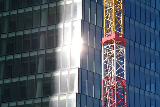 Milan Citylife, Lombardia, about 10/2019.  Construction site tower crane for the construction of the PWC Libeskind skyscraper in Milan. Glass facade with sun reflection.