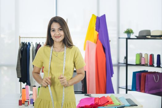 A senior female fashion designer from Asia is working in a textile factory. Confidently with starting a new business And smile at the camera friendly