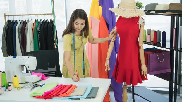 A senior female fashion designer from Asia is working in a textile factory. Confidently with starting a new business