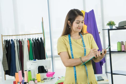 A senior female fashion designer from Asia is working in a textile factory. Confidently with starting a new business And smile at the camera friendly