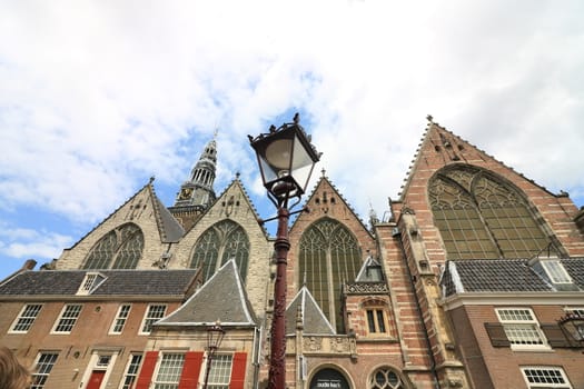 Amsterdam, Netherlands. About the July 2019.  Old Church, Oude Kerk, is the oldest church in the city. It is located on the Oudekerksplein, in the red light district. In the foreground a street lamp.