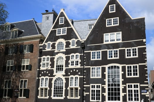 Amsterdam, Netherlands. About the July 2019. Typical Dutch houses seen from the canals of Amsterdam. Facade painted brown with white windows.